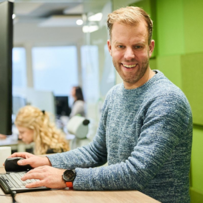 Man in een kantooromgeving die werkt met een ergonomisch hulpmiddel om overbelasting te voorkomen.